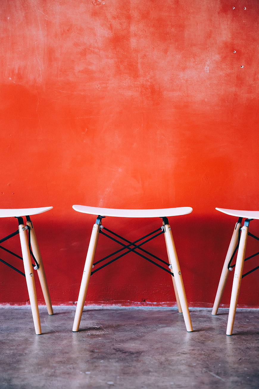 Modern White Stools Against Vibrant Red Wall