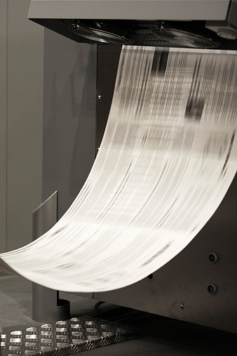 Close-up of industrial offset printing machine with moving paper