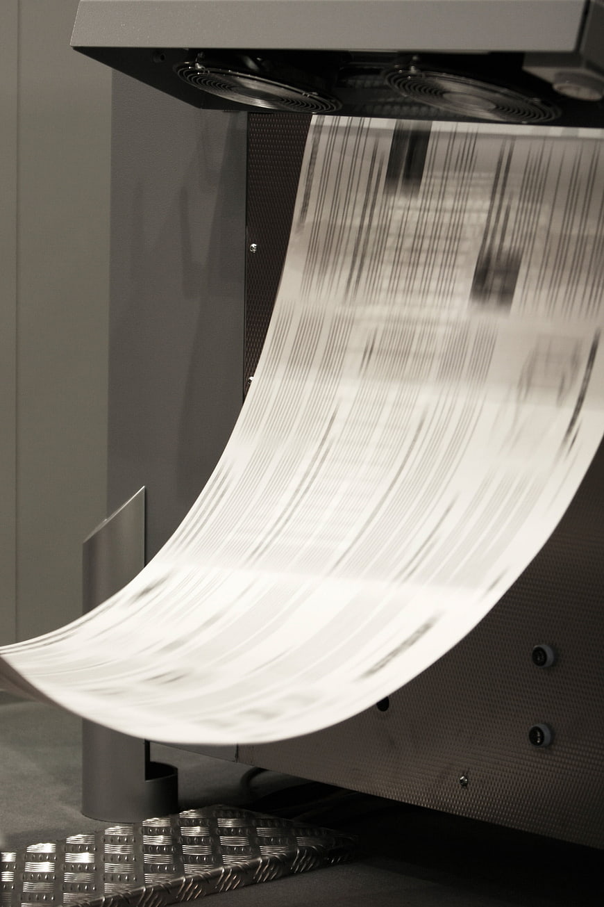 Close-up of industrial offset printing machine with moving paper
