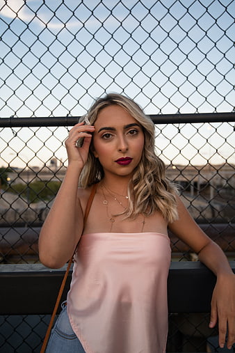 Blonde Woman in Pink Top Leaning on Fence