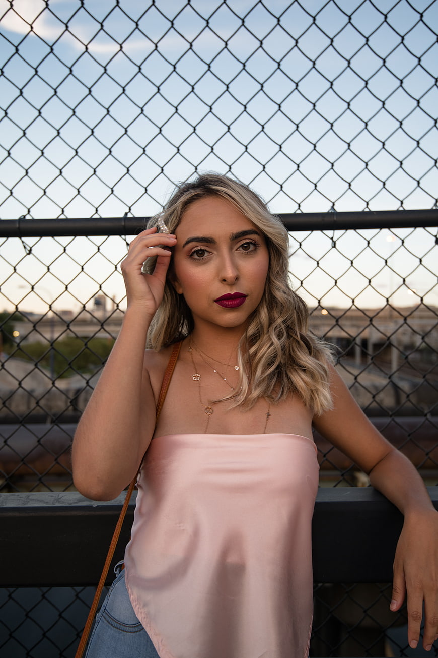 Blonde Woman in Pink Top Leaning on Fence