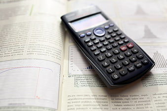 Scientific calculator on open textbook with graphs
