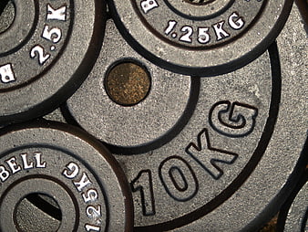 Close-up of stacked gym weight plates with engraved kilograms