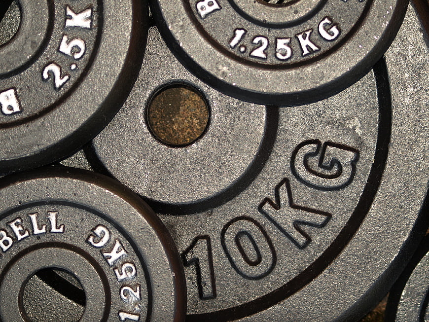 Close-up of stacked gym weight plates with engraved kilograms