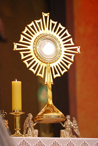 Golden Monstrance with Host and Candle in Church Setting