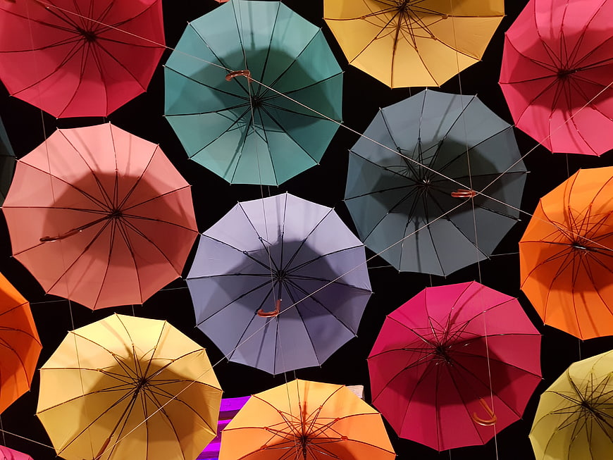 Colorful umbrellas hanging in a pattern against a black background