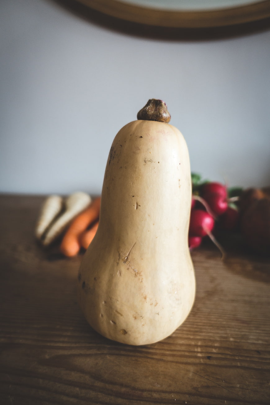 Butternut Squash on Wooden Table with Blurred Vegetables