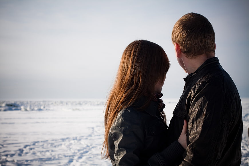 Couple embracing in winter landscape with snowy background