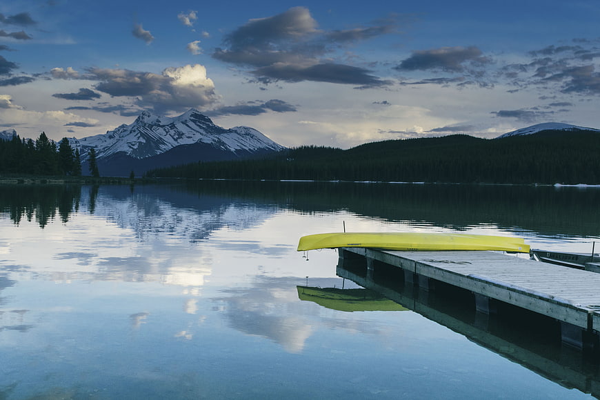 Yellow Kayak on Dock with Snowy Mountain Lake Reflection