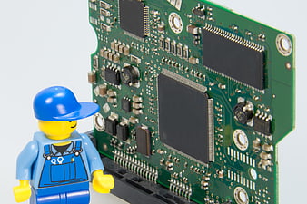 Lego handyman figurine inspecting green circuit board