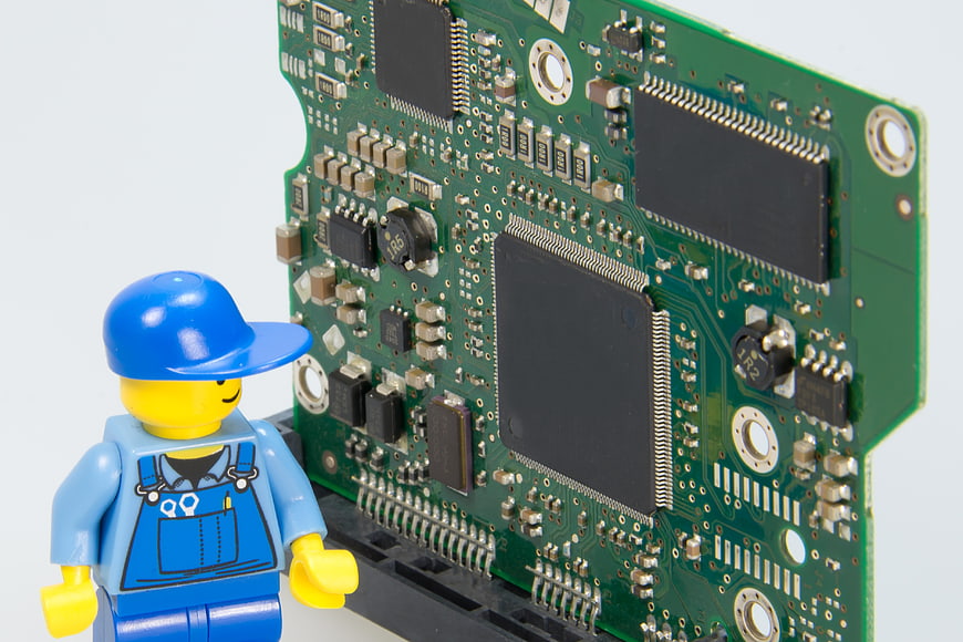 Lego handyman figurine inspecting green circuit board