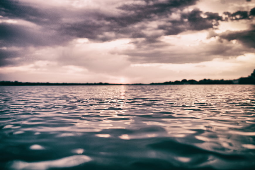 Cinematic Sunset Over Calm Ocean Water with Cloudy Sky