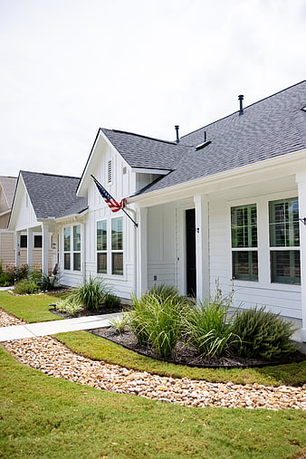 Modern white suburban home exterior with American flag and landscaped yard