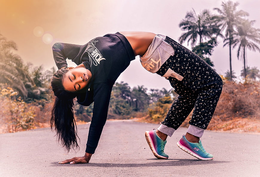 Woman performing backbend yoga pose on road