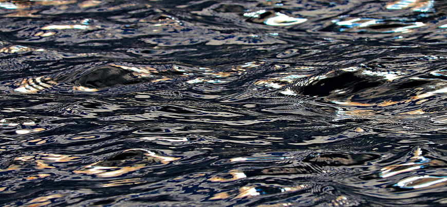 Dark rippling water surface with sunlight reflections