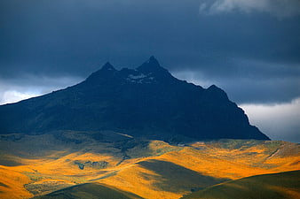 Dramatic Mountain Peak with Golden Sunlit Hills