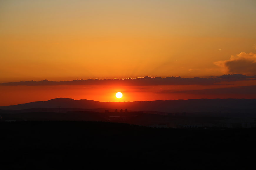 Vibrant Orange Sunset Over Silhouetted Mountain Landscape