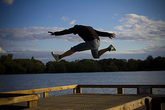 Man Jumping Off Wooden Dock Into Lake