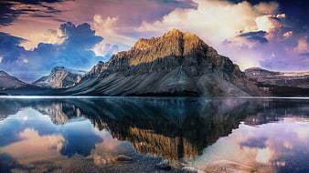 Majestic Mountain Peak Reflected in Calm Lake Under Dramatic Purple Sky