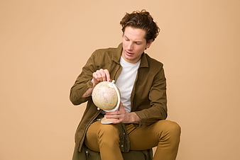 Young man examining a globe in a studio setting