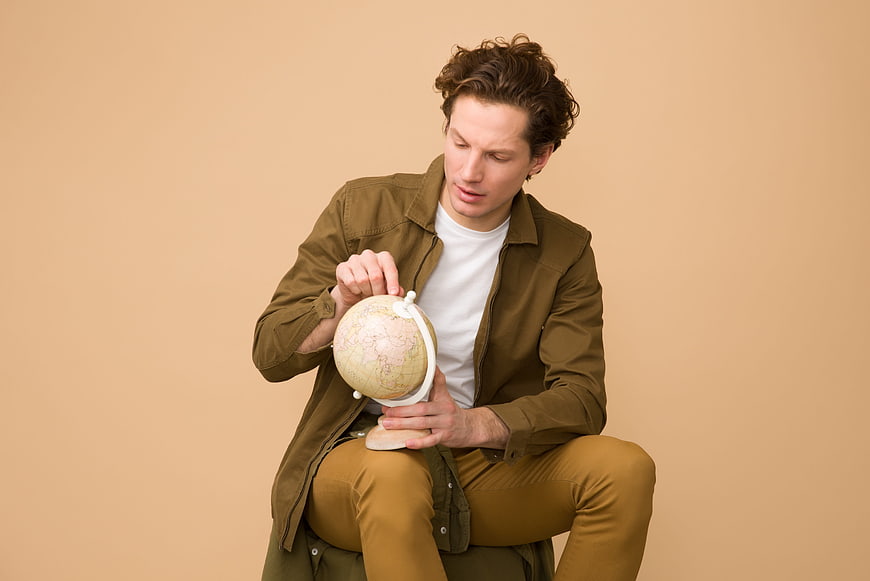 Young man examining a globe in a studio setting