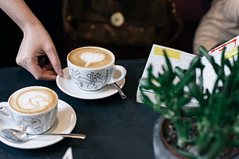 Two cups of cappuccino with latte art on a cafe table