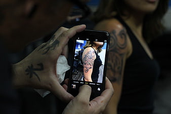 Tattoo Artist Photographing Finished Sleeve Tattoo on Smartphone