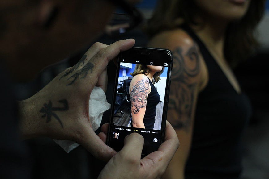 Tattoo Artist Photographing Finished Sleeve Tattoo on Smartphone