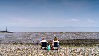 Senior couple sitting on beach chairs watching the ocean horizon