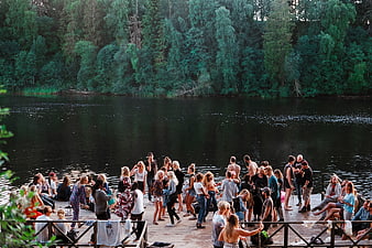 Large group of young people partying on a wooden dock by a lake