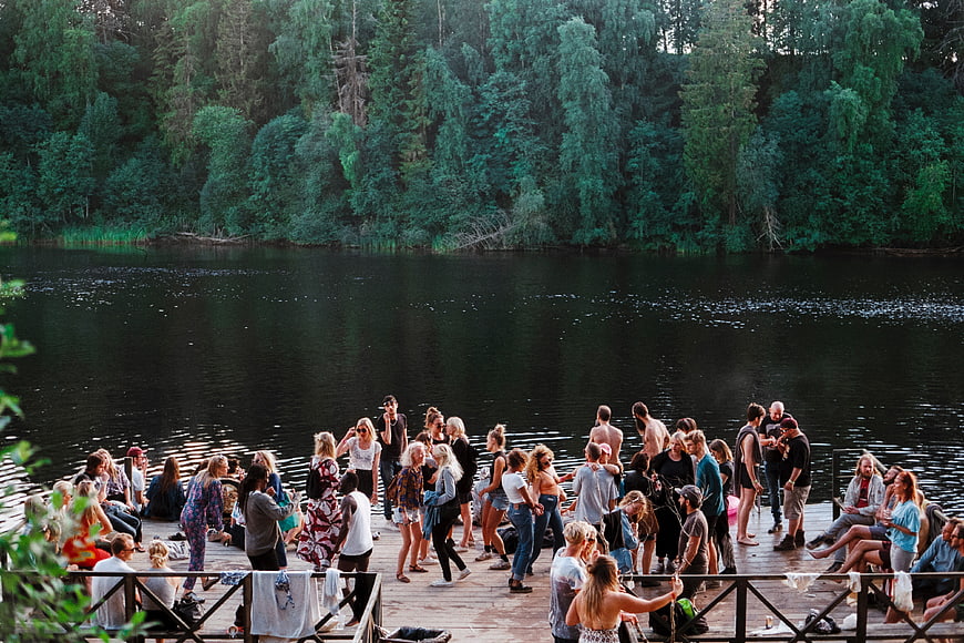Large group of young people partying on a wooden dock by a lake