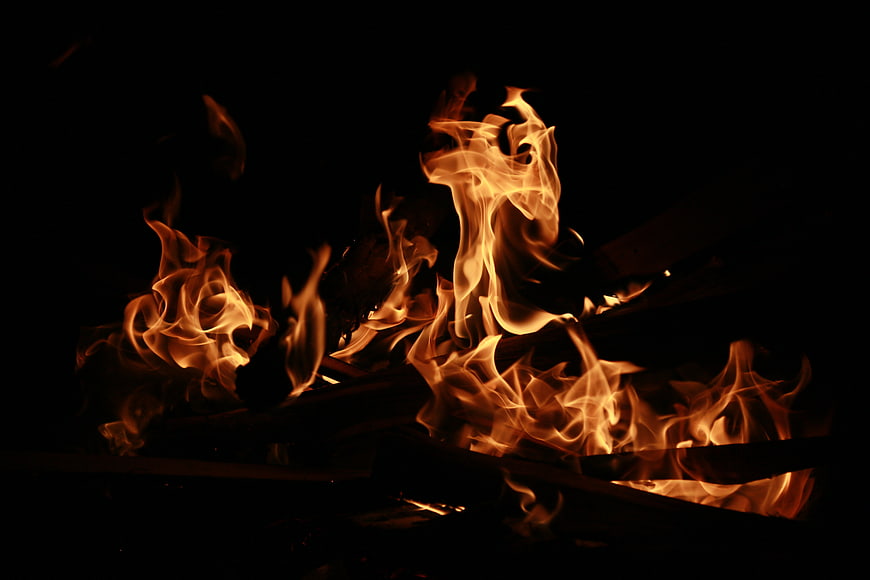 Close-up of burning wood logs in a dark fireplace