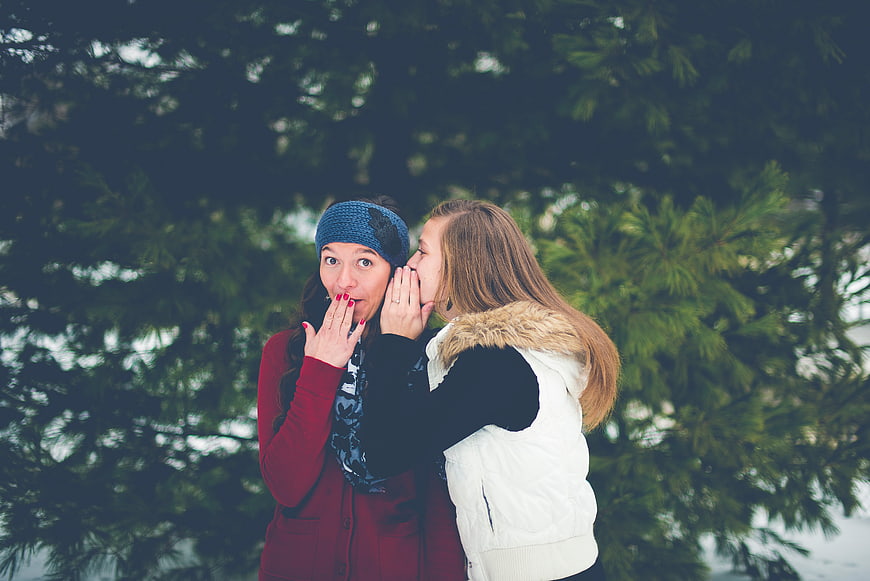 Two women whispering secrets outdoors in winter