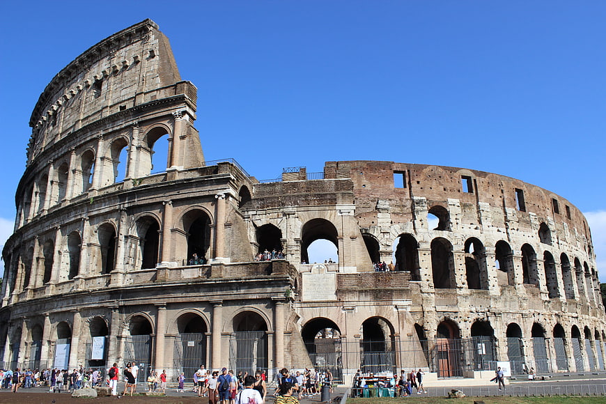 Colosseum in Rome, Italy, with tourists under a clear blue sky