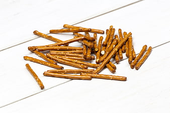Salted pretzel sticks on white wooden background