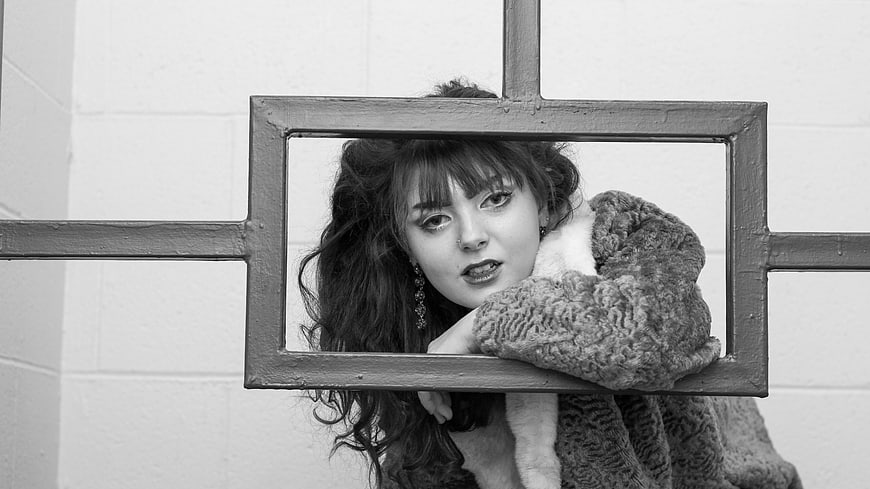 Black and white portrait of woman looking through window frame