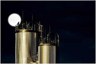 Industrial Storage Tanks Silhouetted Against Full Moon At Night