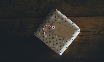 Wrapped gift box with tag on dark wooden background