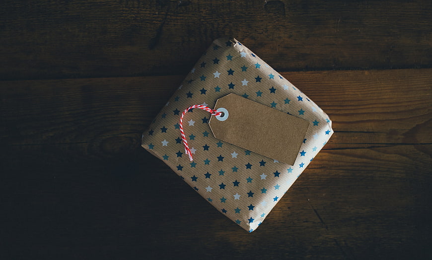 Wrapped gift box with tag on dark wooden background