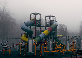 Empty playground with colorful slides in thick fog