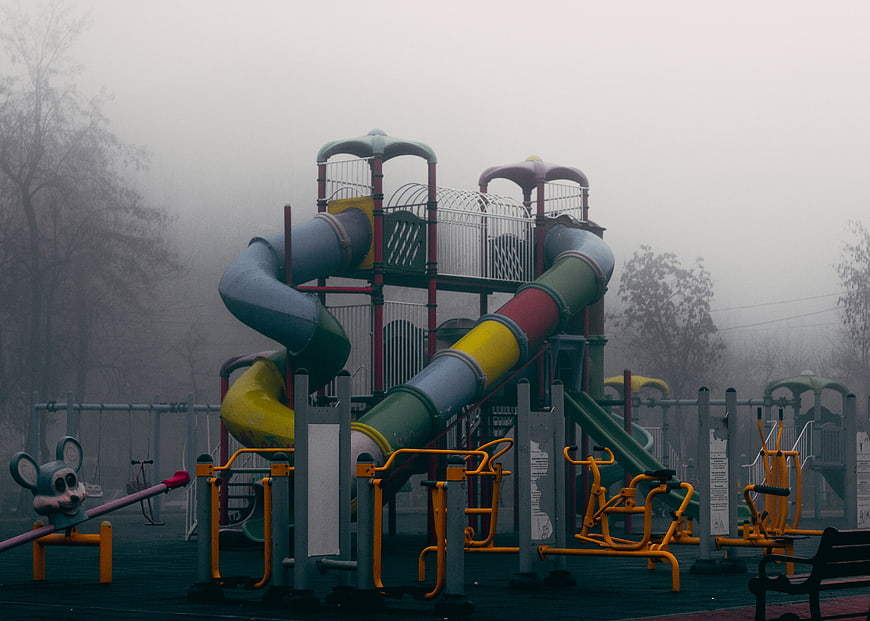 Empty playground with colorful slides in thick fog