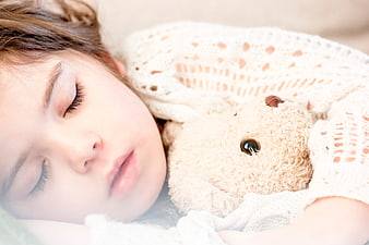 Close-up of sleeping child hugging teddy bear