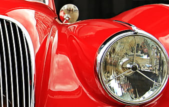 Close-up of vintage red car headlight and chrome grille