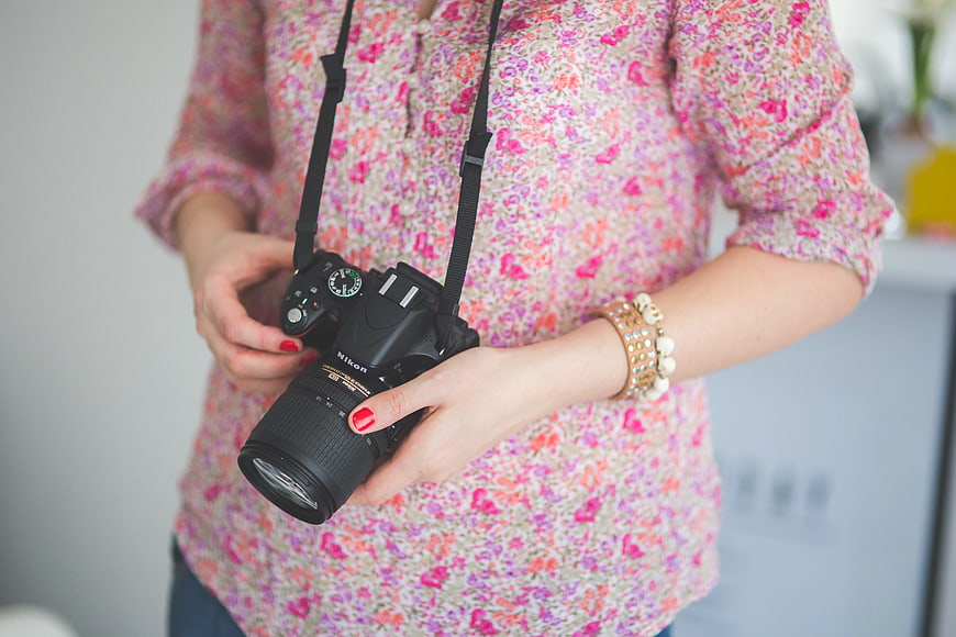 Woman holding DSLR camera with floral shirt