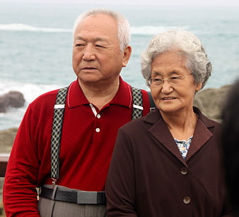 Senior Asian couple standing together outdoors near the ocean