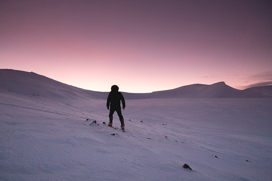 Silhouette of snowshoer in snowy landscape at dusk