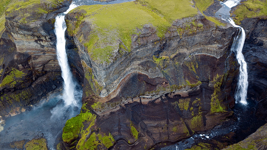 Aerial View of Twin Waterfalls Cascading Over Mossy Cliffs in Iceland