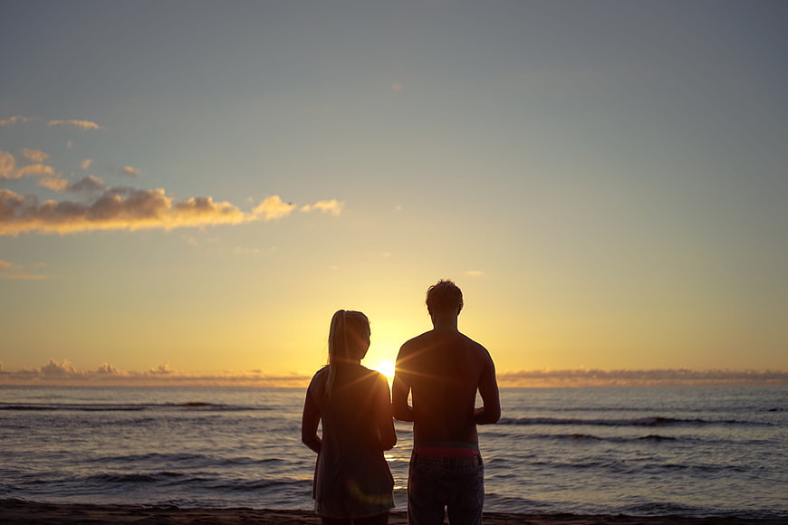 Silhouette of couple watching sunset over ocean