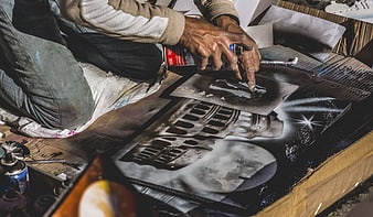 Street artist spray painting stencil art on cardboard