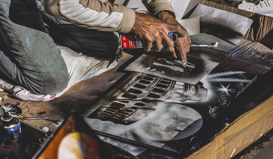 Street artist spray painting stencil art on cardboard